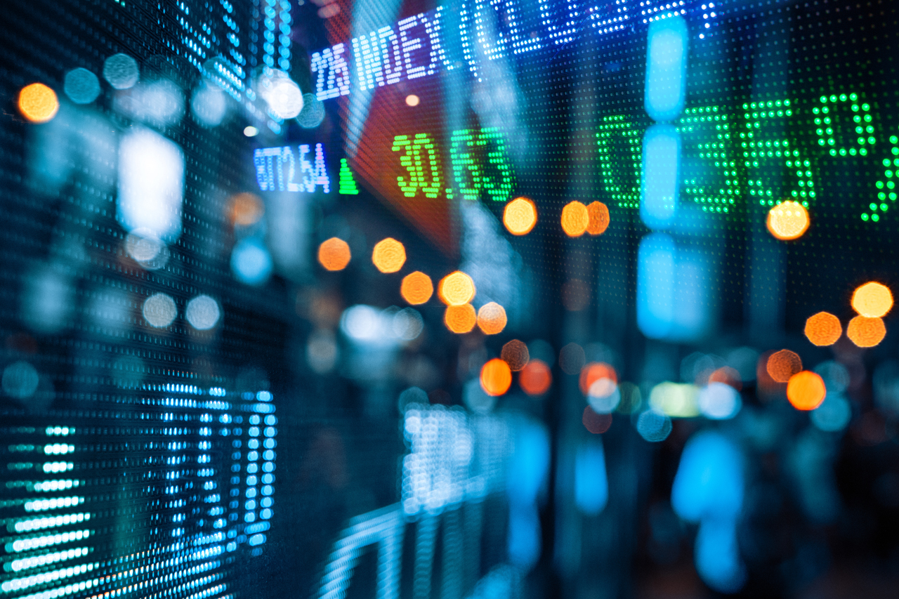 A stock ticker in the foreground with a prismatic light treatment applied.