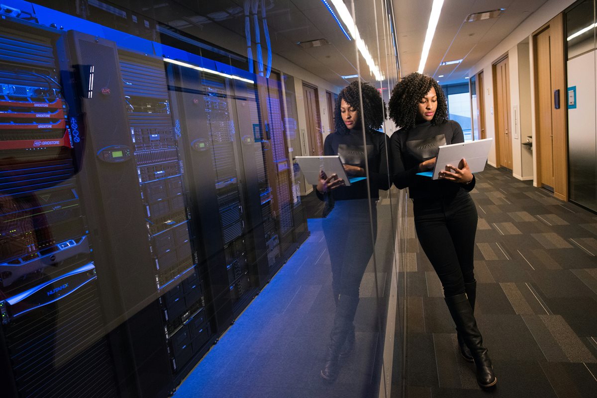 A person looking at a computer outside of some server racks