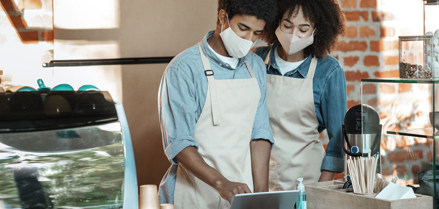 Two people in aprons looking at computer