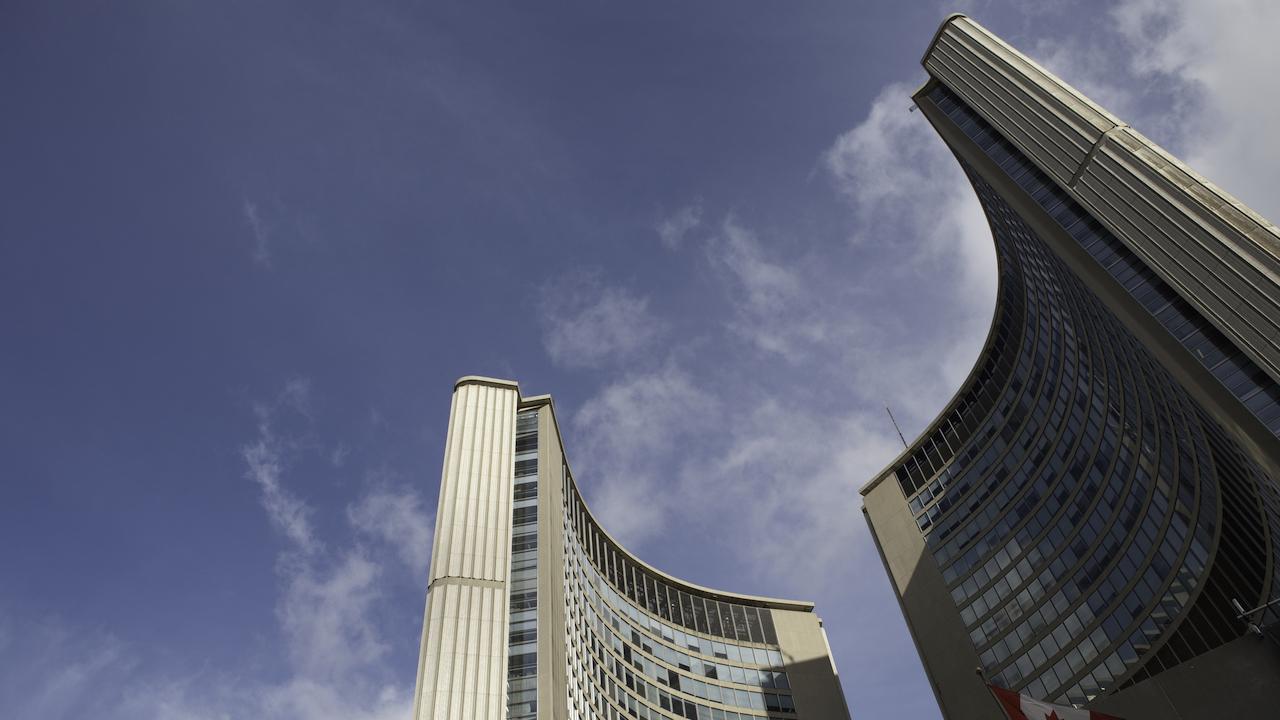 A low-angle shot of City Hall in front of a blue, cloudy sky.