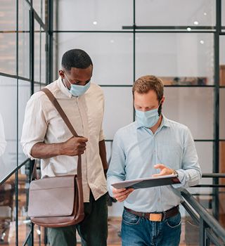 Masked coworkers viewing a tablet.