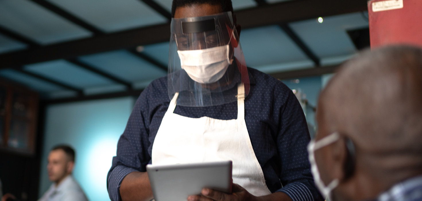 fully masked waiter checking ipad