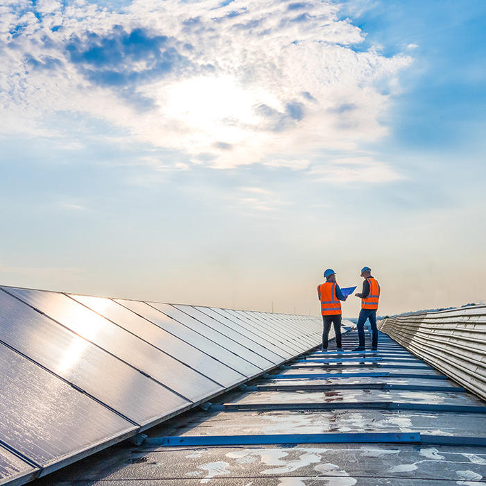 Guys working on solar panels under a partially cloudy sky.